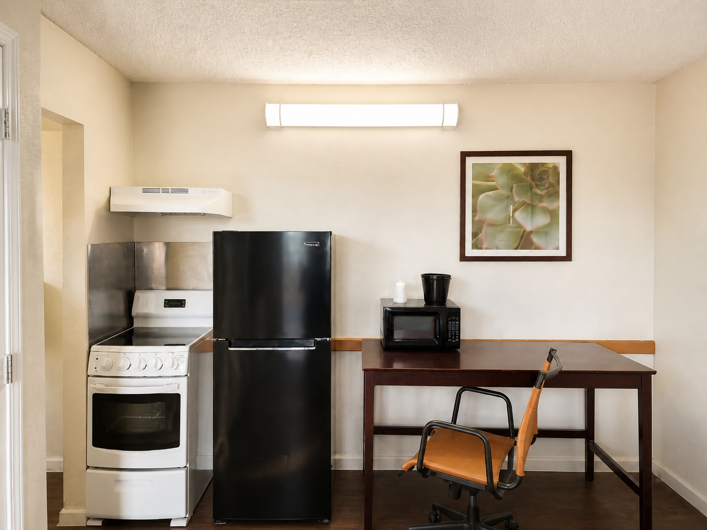 Montgomery kitchenette with refrigerator, stove, microwave, and workspace